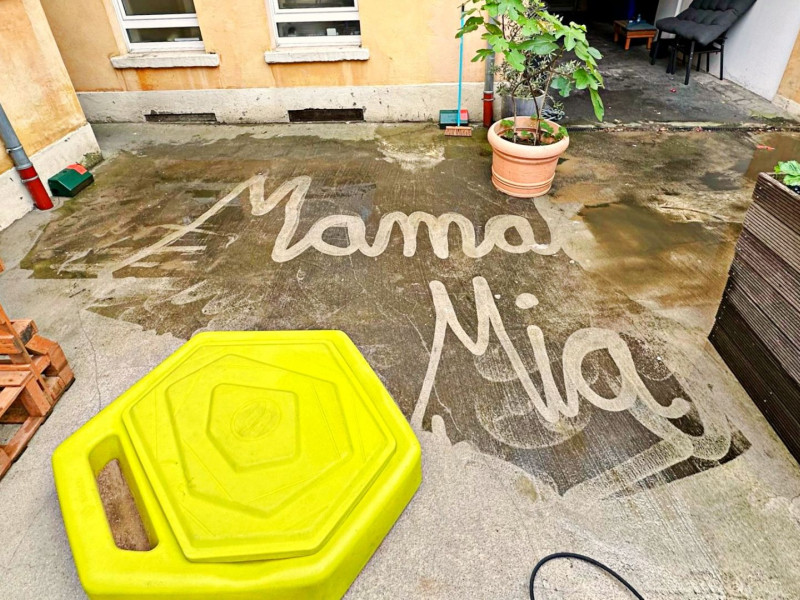 Mit Wasser auf Beton geschriebener Schriftzug ‚Mama Mia‘ in einem Innenhof