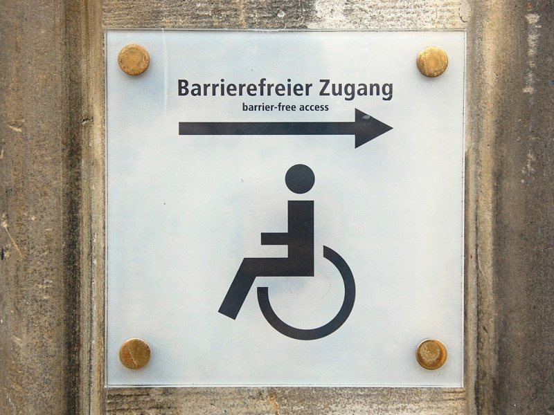 Hinweisschild „Barrierefreier Zugang“ mit Rollstuhlsymbol und Pfeil nach rechts