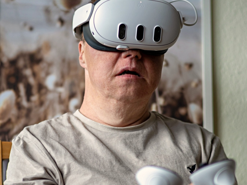Mann nutzt eine VR-Brille mit zwei Controllern