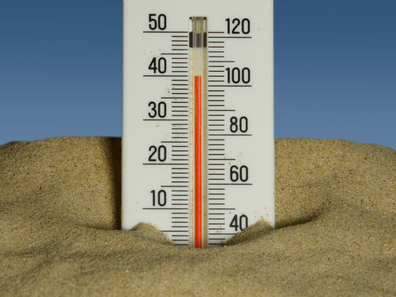 Thermometer im Sand zeigt hohe Temperaturen von rund 35 Grad Celsius.