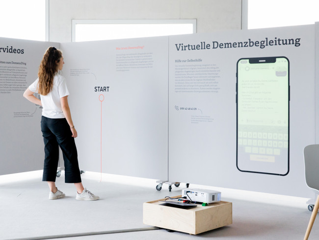 Eine Frau steht in der "DemenzDinge"-Ausstellung und liest aufmerksam einen Text zu einem der umgesetzten Projekte