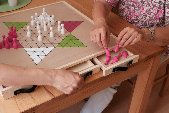 Zwei Personen spielen das optimierte Gesellschaftsspiel für Menschen mit Demenz, "DemenzDing Halma"