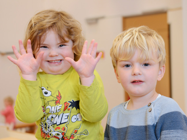 Zwei lachende Kinder posieren fröhlich für die Kamera im Kinderzentrum.