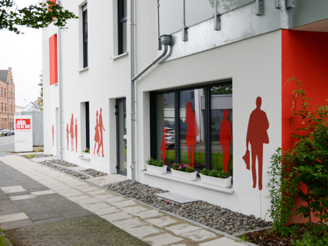 Das Gebäude der Notfall-Schlafstelle Siegburg mit roten Silhouetten an der Fassade.