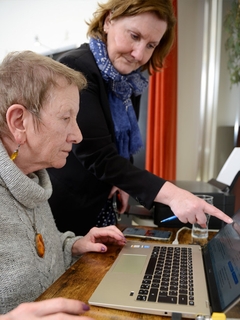 Zwei Frauen arbeiten zusammen an einem Laptop. Eine zeigt der anderen etwas.