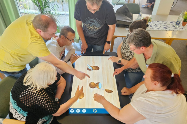 Gruppe von Senior:innen am digitalen Aktivitätstisch.