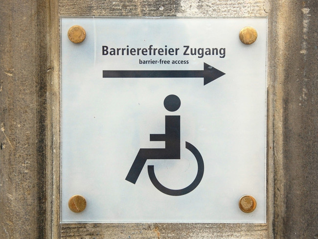 Hinweisschild „Barrierefreier Zugang“ mit Rollstuhlsymbol und Pfeil nach rechts