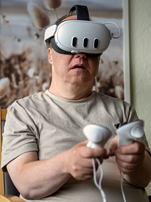 Mann nutzt eine VR-Brille mit zwei Controllern