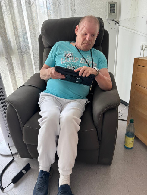Mann sitzt im Sessel und bedient konzentriert ein Tablet.