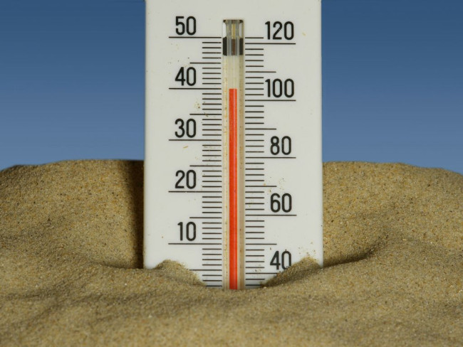 Thermometer im Sand zeigt hohe Temperaturen von rund 35 Grad Celsius.